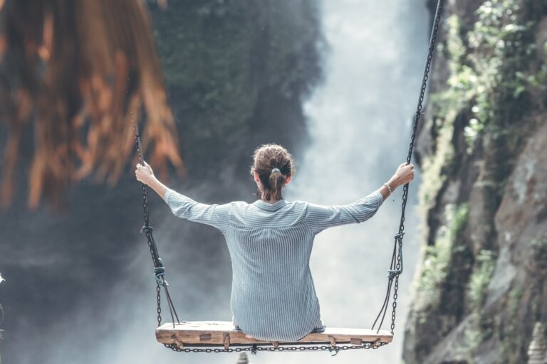 A relieved person enjoying peace of mind, while swinging in front of a waterfall