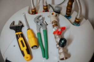 A close-up, high-angle view showcases an adjustable wrench, screwdriver, and pliers alongside pipes, fittings, and valves, suggesting meticulous plumbing repair or maintenance in progress.