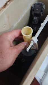 Close-up of a toilet cistern with the flush valve removed during an inspection to diagnose a toilet that keeps running and wasting water.