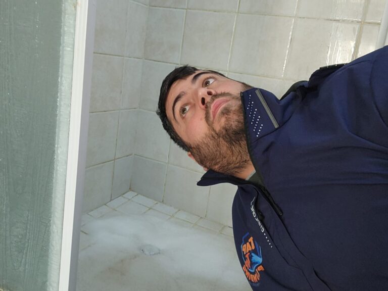 Homeowner listening for gurgling sounds from a shower drain to check for a developing blocked drain and restricted water flow.