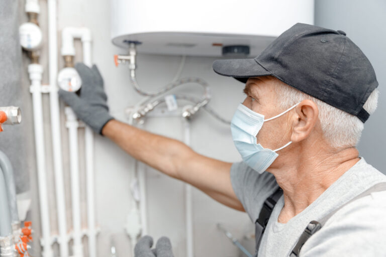 Male plumber in medical mask checks pipes for emergency appointment
