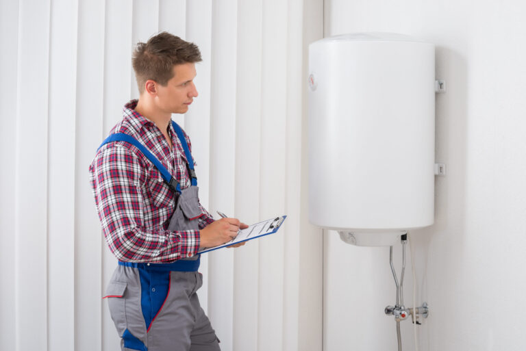 Young Male Plumber Holding Clipboard Checking Electric Boiler